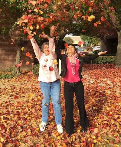 Two women throwing leaves in the air.
